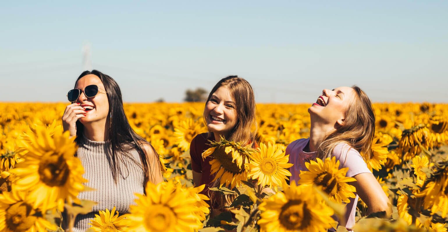 Image claire et agrandie de trois femmes debout dans un champ de tournesols.